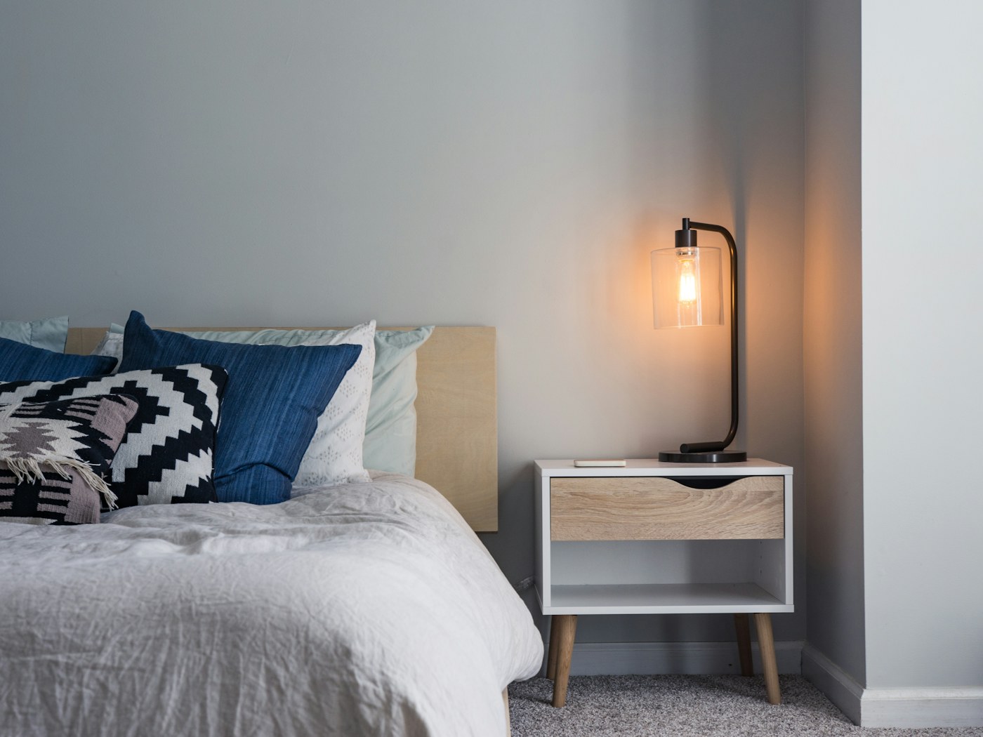 Person reading in bed beside a warm shaded lamp